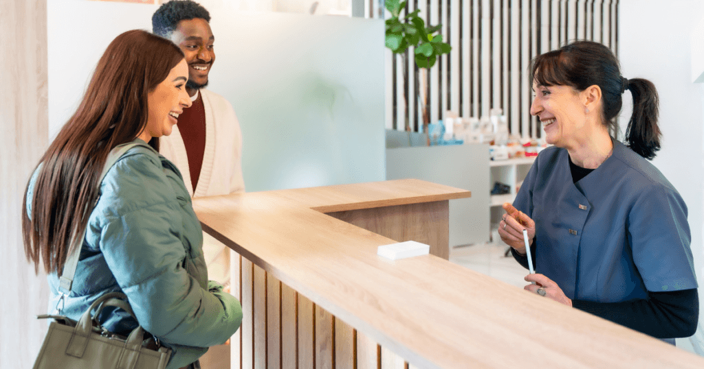 Dental receptionist checking in patient with welcoming front desk